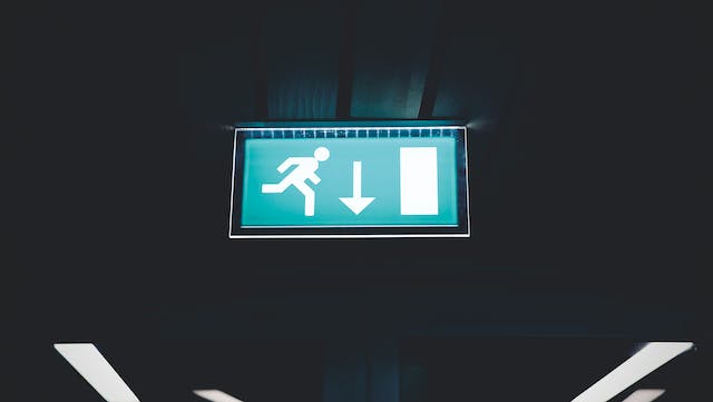 A lit up sign pointing to a fire escape.