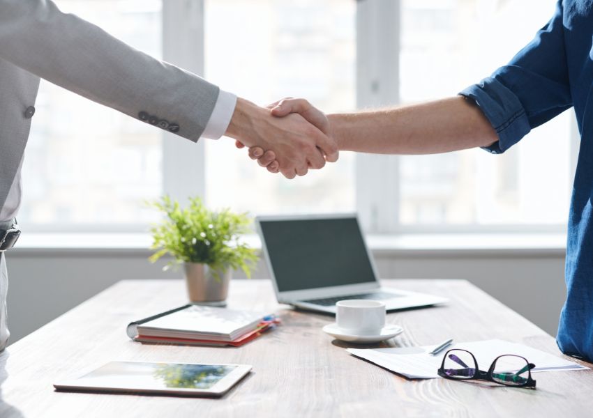 two-people-shaking-hands-over-table